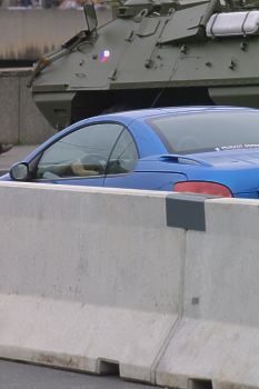Auto mezi betonovou zdí a transportérem